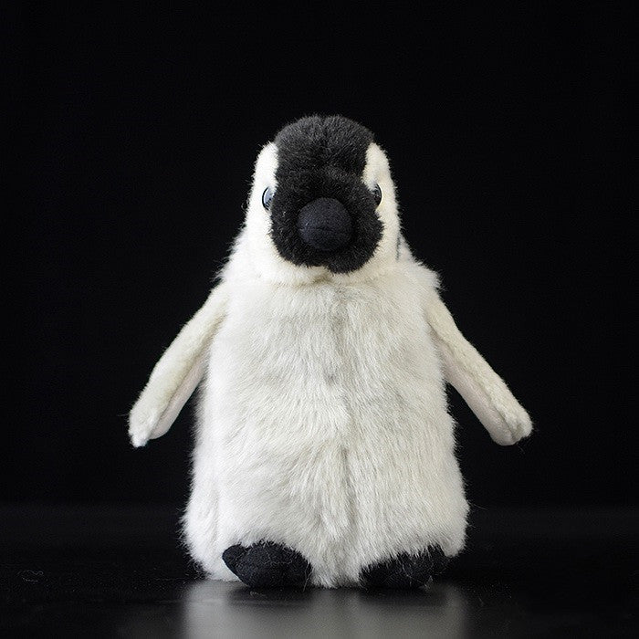 Cute plush penguin toy with white and black fur stands against a dark background, featuring a round face, small wings, and black feet.