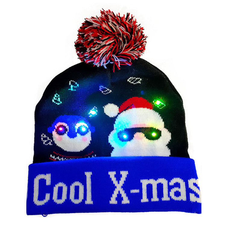 Christmas beanie with "Cool X-mas" text, featuring a light-up penguin and Santa wearing sunglasses. The hat is topped with a red and white pom-pom.