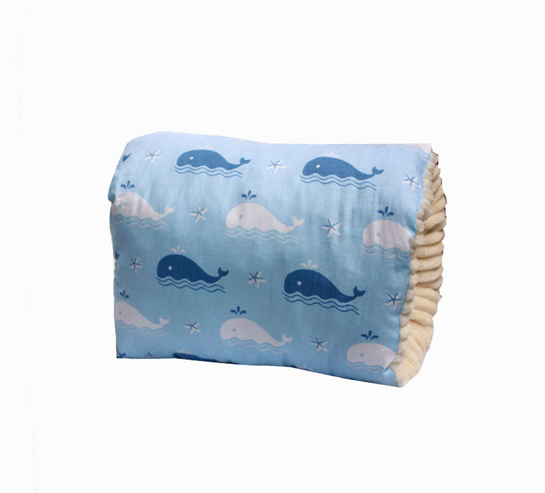 A light blue pillow covered with whale and star patterns in varying shades of blue and white on a crinkled, cushion-like surface.