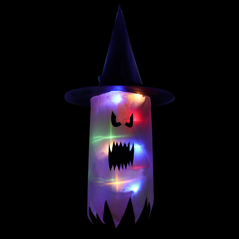 A glowing ghost with angry eyes and a jagged mouth, wearing a pointed witch hat. It is illuminated with vibrant, multicolored lights against a black background.
