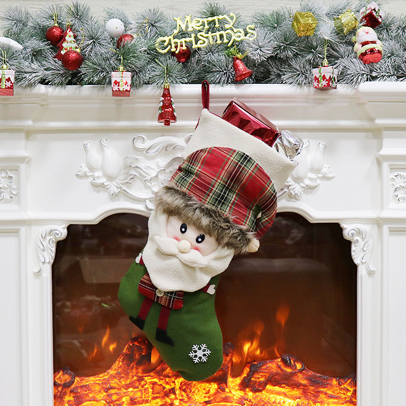 Festive fireplace with a Santa-themed stocking filled with gifts hangs above a glowing hearth. The mantle is decorated with pine garland, ornaments, and "Merry Christmas" text.