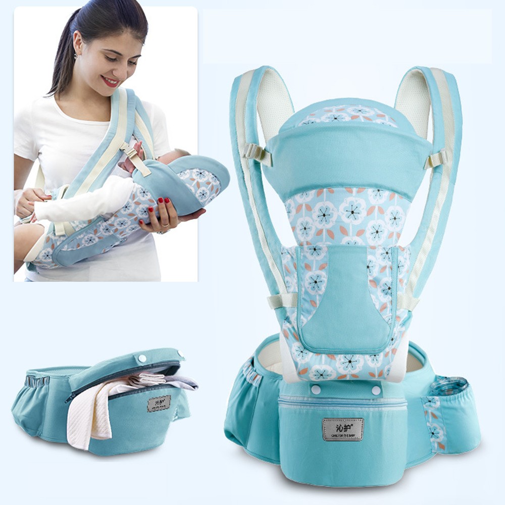A woman uses a blue floral-patterned baby carrier, holding a baby. The carrier features adjustable straps and a waistband with pockets. Close-up showing carrier's design and accessories.