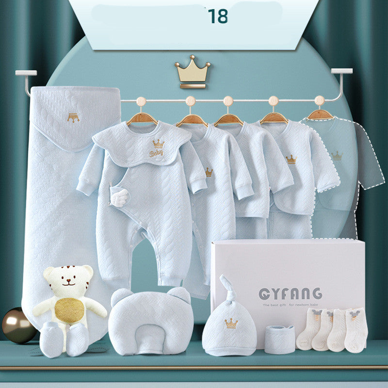 Baby clothing set in soft blue, featuring a romper, jackets, hat, socks, and matching accessories, adorned with crown motifs. Includes a plush toy and gift box.