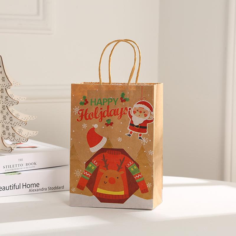 Festive holiday gift bag with "Happy Holidays" text, featuring a reindeer sweater, Santa graphic, and snowflakes. It sits on a table near white books and a decorative tree.