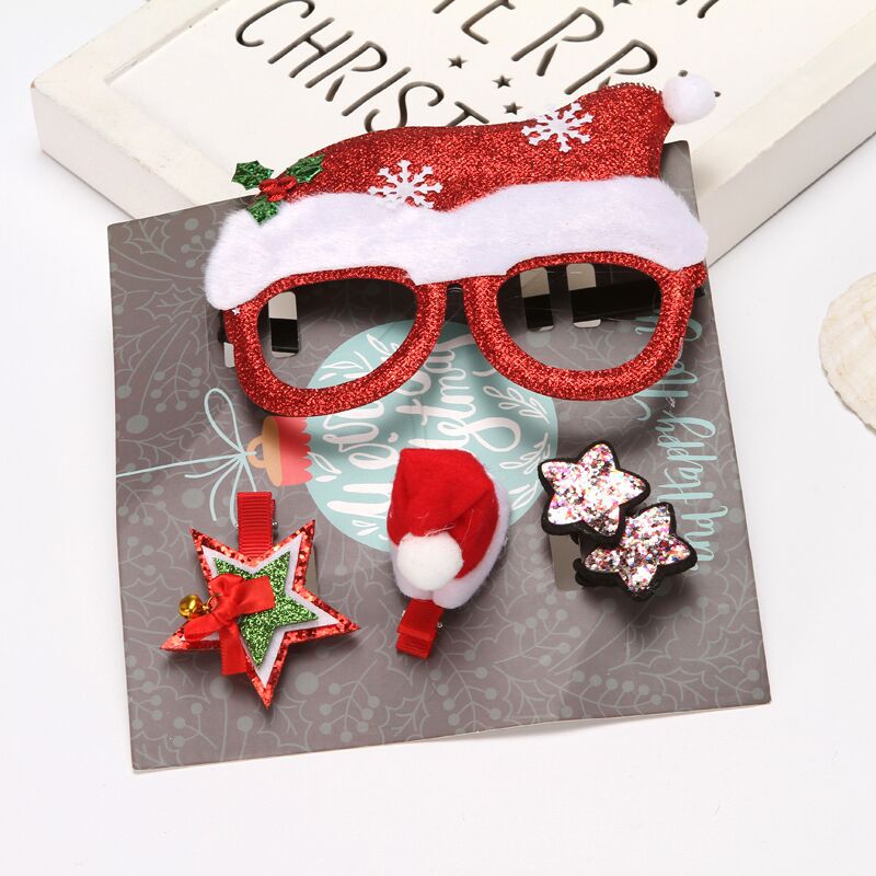 Festive accessories set includes red glittery glasses with a Santa hat design, a red and green star clip, a mini Santa hat clip, and sparkly star hairpins on a decorative card.