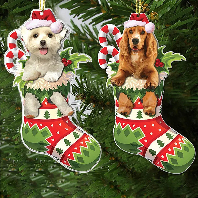 Two Christmas ornaments featuring dogs in festive stockings with candy canes and holly, hanging on a green Christmas tree. One dog is white, the other is brown.