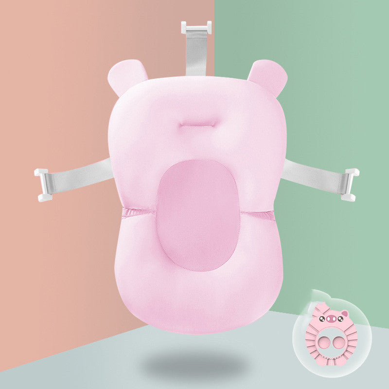 Pink baby bath seat with bear ears and secure straps, positioned against a half peach, half green background. A small, round, pink toy is displayed in the lower right corner.