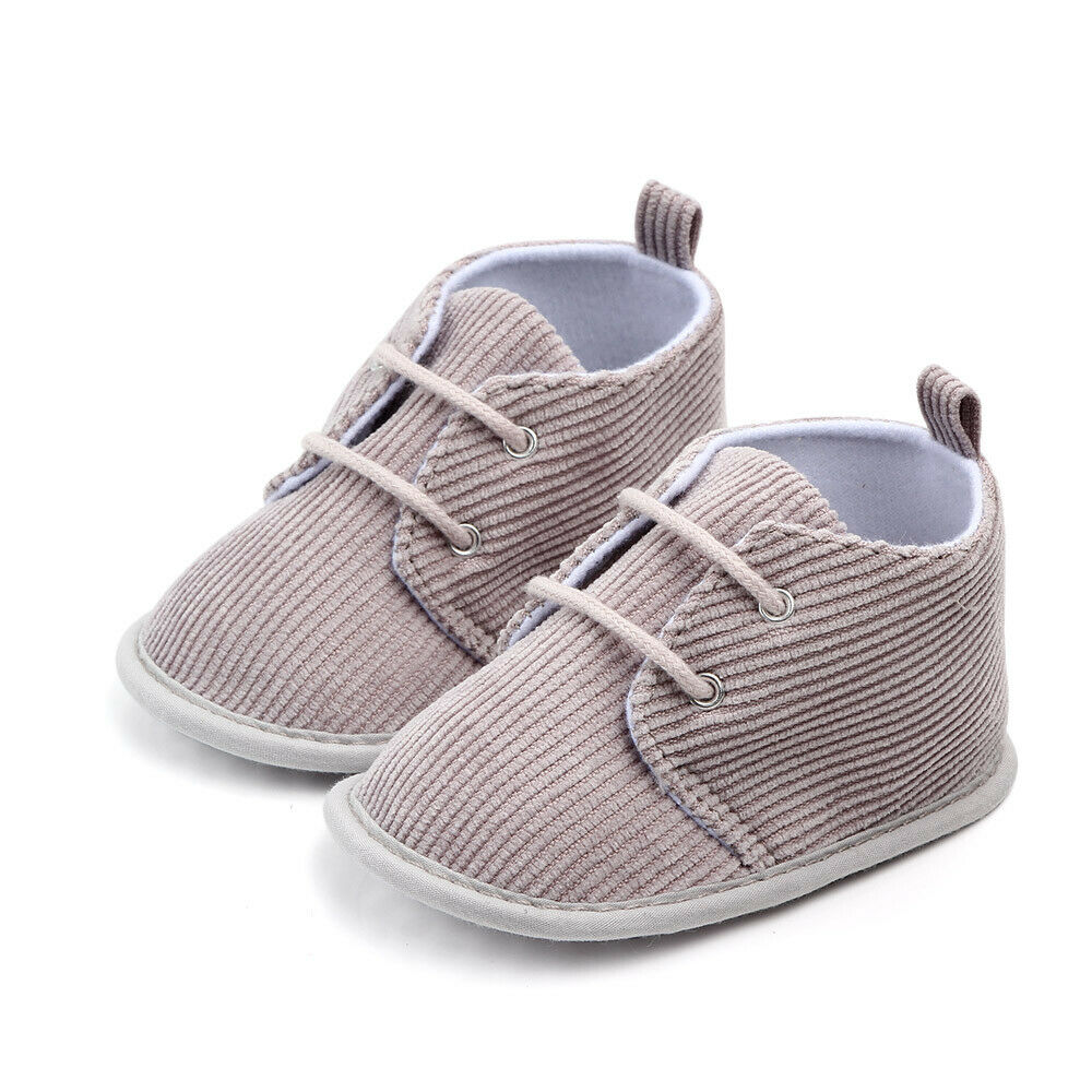 Gray corduroy baby shoes with white soles and laces, featuring a soft interior and pull tabs at the back. Perfect for infants, stylish and comfortable.