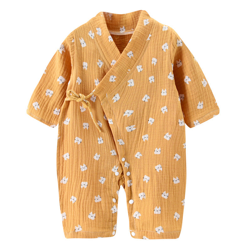 Baby romper in soft orange fabric with a wrap style and tie closure. Features a white cat face pattern. Short sleeves and leg openings are adorned with white snaps.