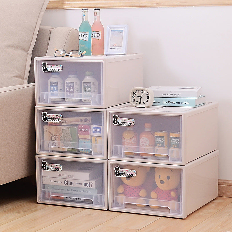 Stacked beige storage drawers filled with drinks, books, and teddy bears are next to a sofa. A small clock, books, framed photo, and colorful bottles sit on top.