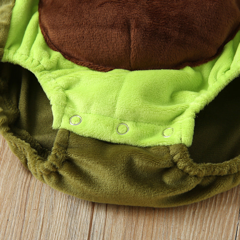 Close-up of a plush, green and brown fabric with snap buttons, resembling a costume or garment, displayed on a wooden surface.