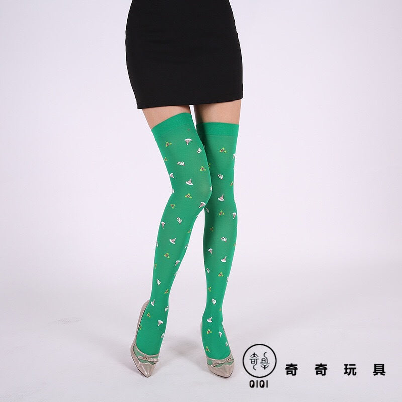 Woman wearing green knee-high socks with small floral patterns, paired with a black skirt and silver heels. Background is plain white.