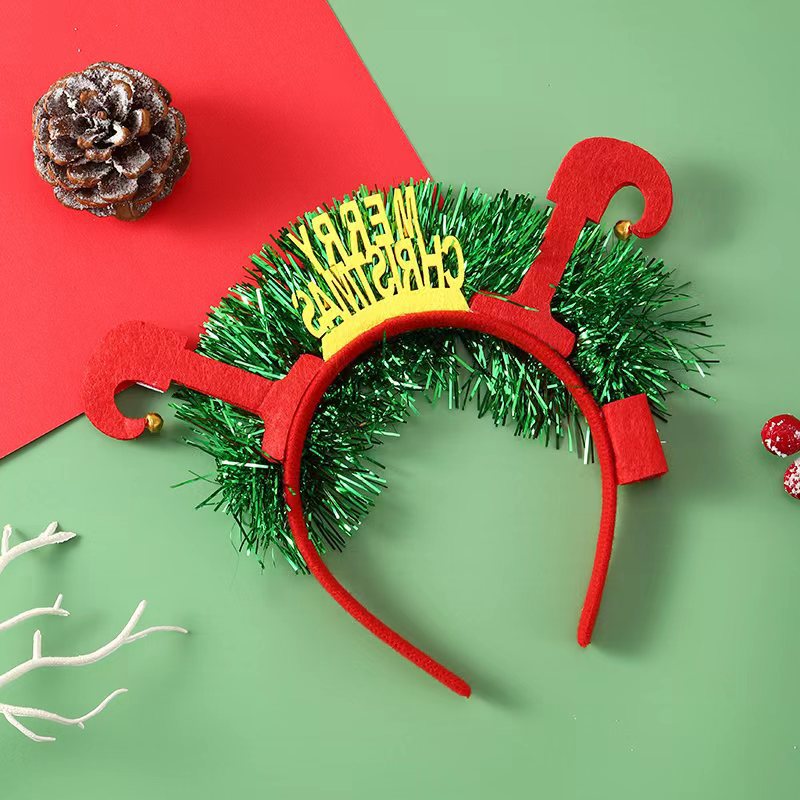 Festive red headband with green tinsel and "Merry Christmas" text, surrounded by a snowy pine cone, red berries, and white twigs on a red and green background.