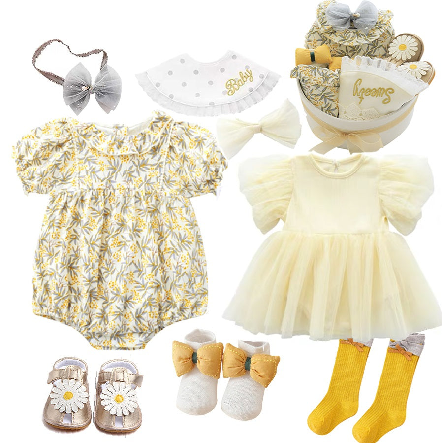 Yellow floral baby romper, cream puff sleeve dress, gold bow socks, daisy sandals, headbands, yellow socks, and gift box with "Baby" bib.