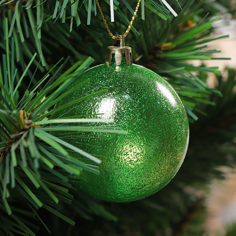 A sparkling green ornament hangs on a Christmas tree branch, reflecting light and surrounded by lush green pine needles.