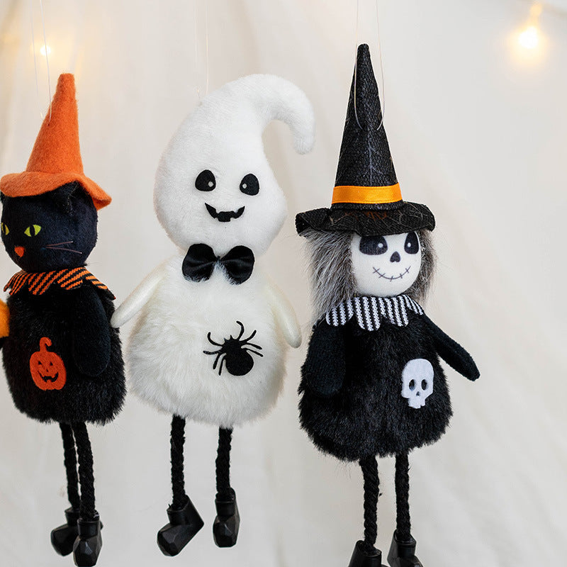 Three hanging Halloween-themed plush toys: a cat in an orange hat, a ghost with a bow tie, and a skeleton in a witch hat, all set against a white background with lights.