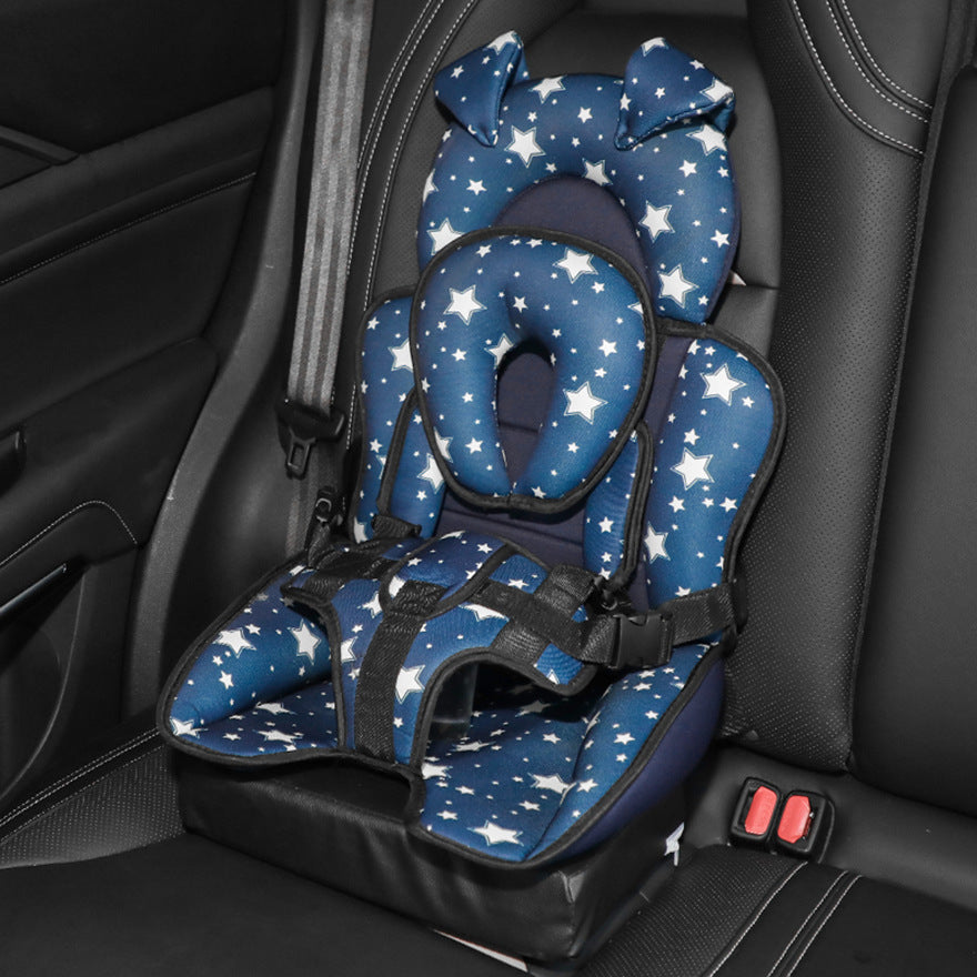 Blue star-patterned child car seat with padded headrest and safety harness, set on a black leather car seat.
