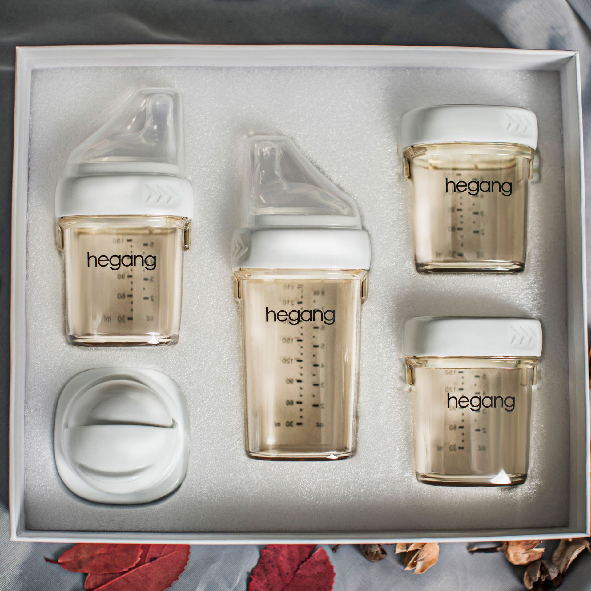 Set of five transparent hegong containers with white lids, arranged neatly in a box with foam padding. Each container has measurements marked.