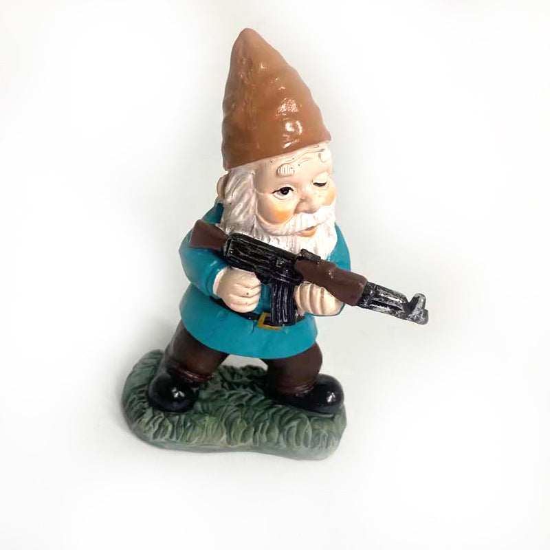 Gnome figure in a blue coat and brown hat, holding a rifle, stands on green base. The gnome has a white beard and a determined expression.