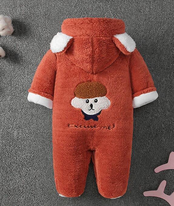 A fluffy, rust-colored baby romper with a hood featuring white ears. It has an embroidered cute bear face and the text "excuse me!" on the back, displayed on a gray surface.