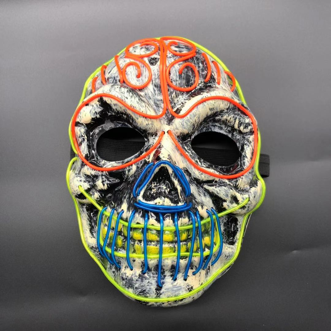 Colorful skull mask with swirling neon accents in orange, blue, and yellow on a textured black and white surface, set against a plain dark background.