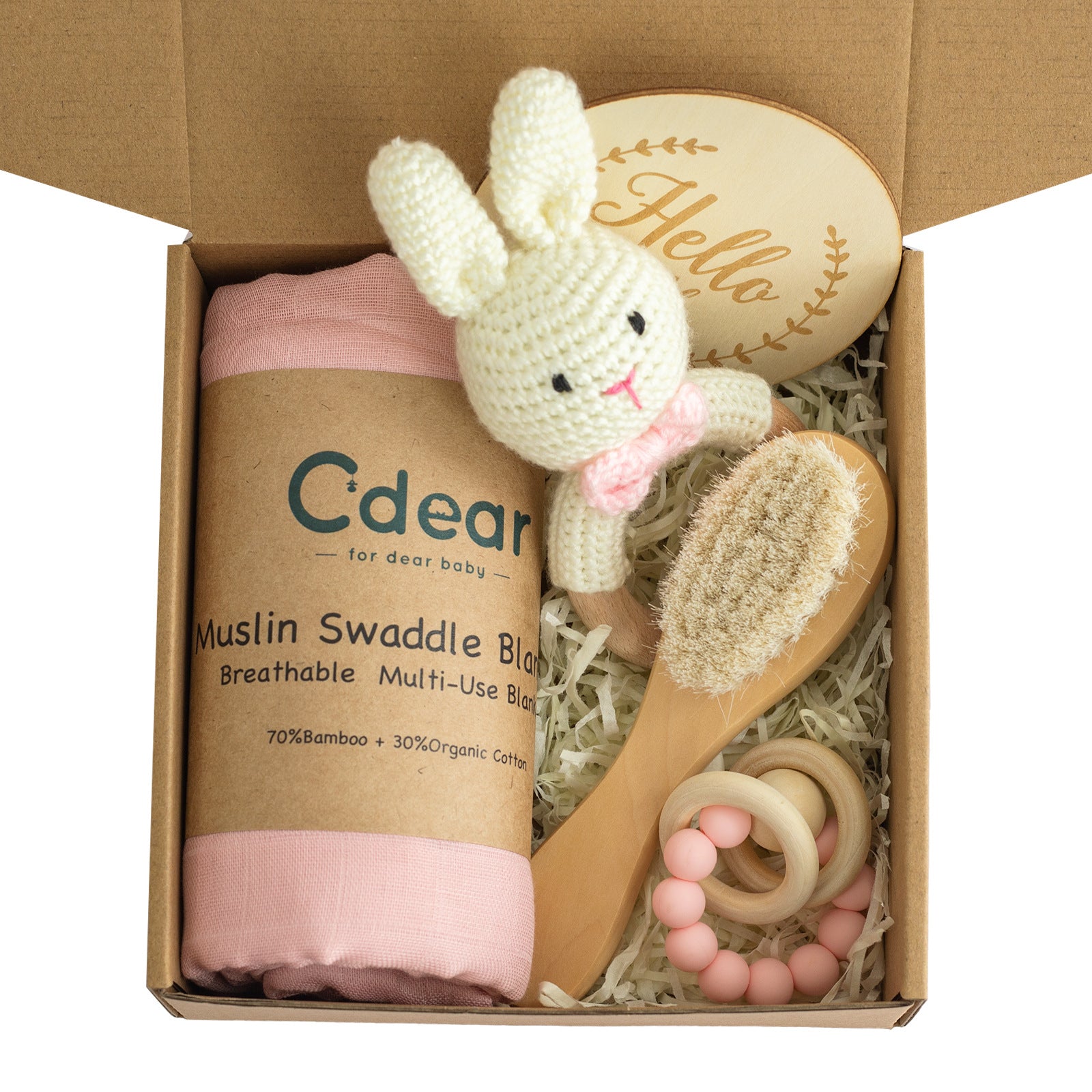 Gift box containing a pink muslin swaddle blanket, a crochet bunny toy, a wooden baby brush, a wooden rattle with pink beads, and a wooden plaque with "Hello" engraved.