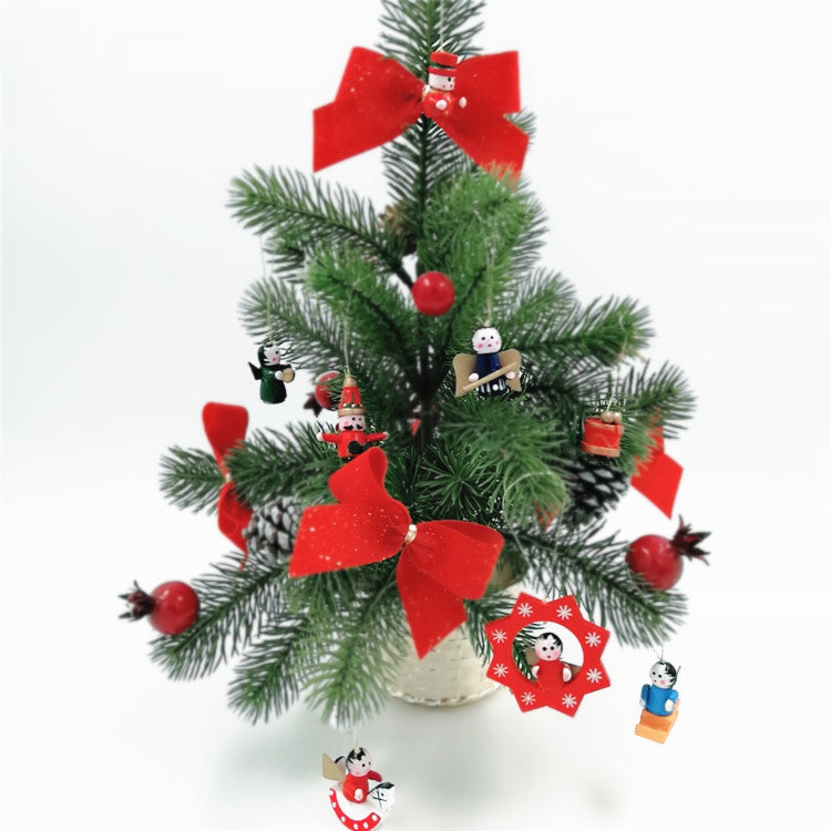 A small Christmas tree decorated with red bows, miniature ornaments, and tiny figurines, set in a white pot. The tree features pine branches and occasional red berries.