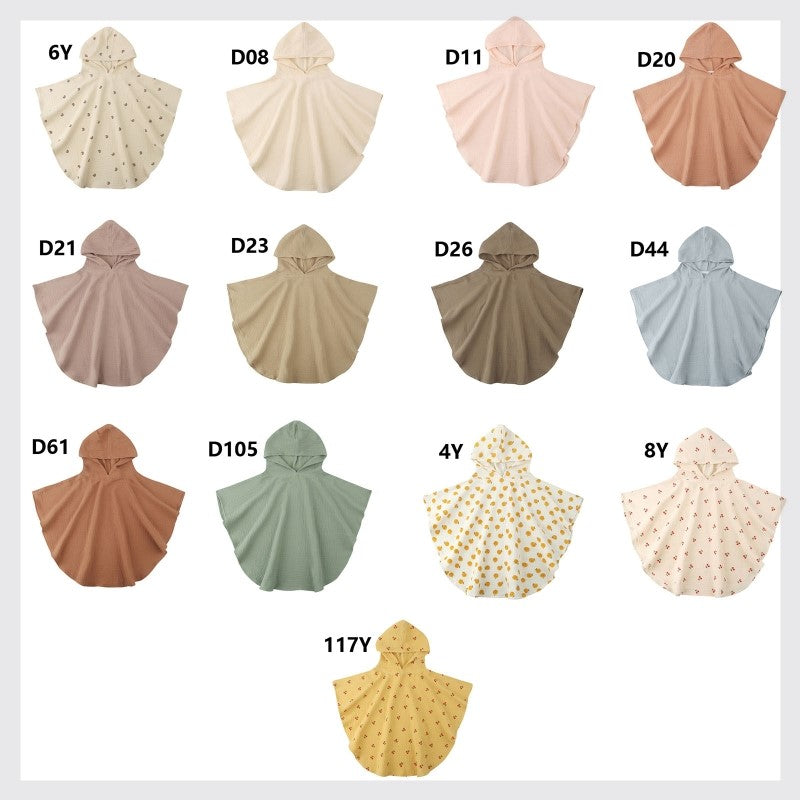 A display of 14 child-sized hooded ponchos in various solid colors and patterns, including polka dots and floral designs, arranged in four rows with labels above each poncho.