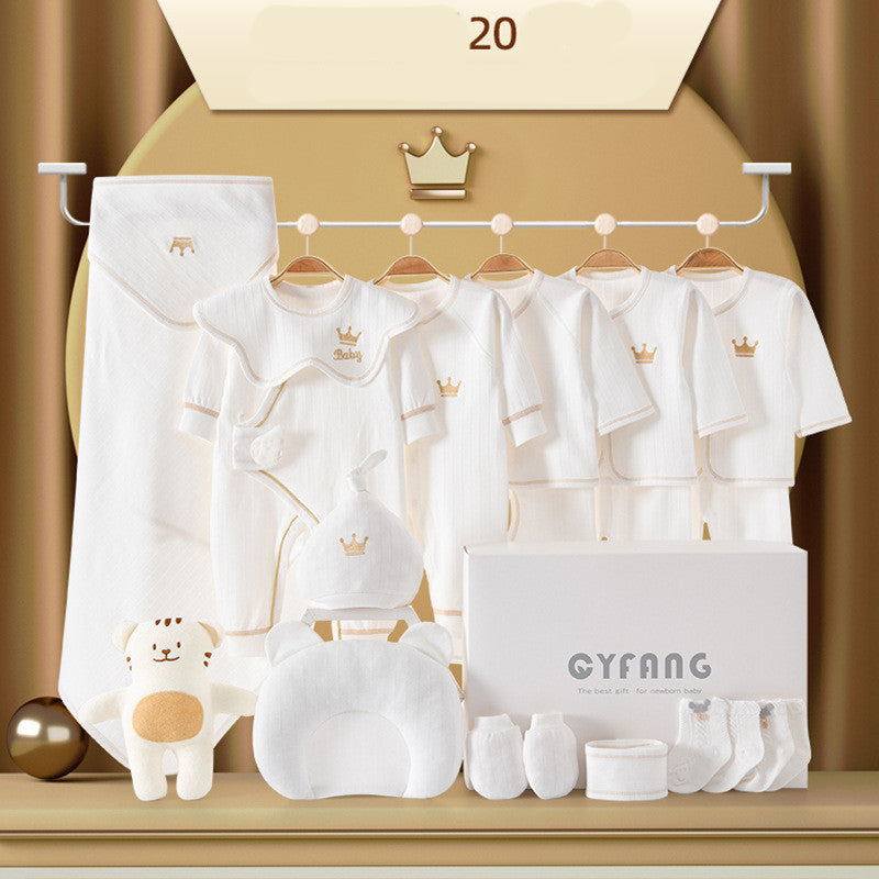 A complete newborn gift set featuring white baby outfits with crown motifs, a plush bear toy, a pillow, socks, and accessories, all elegantly displayed on hangers and in a gift box.
