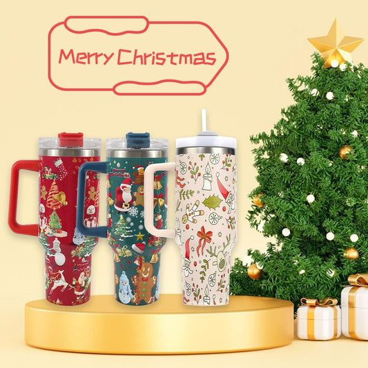 Three festive travel mugs with Christmas-themed designs are displayed on a golden pedestal. A decorated Christmas tree and wrapped gifts are in the background, with "Merry Christmas" above.