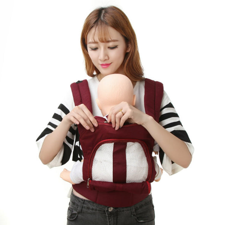 A person wearing a striped top carries a baby mannequin in a maroon baby carrier with a mesh front pocket. The background is plain white.