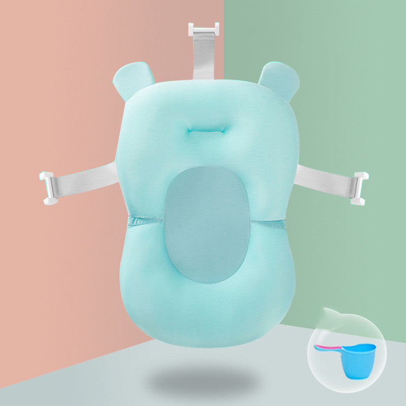 A blue, bear-shaped baby bath cushion with white straps, designed to provide comfort during bathing. It is shown against a split peach and green background.