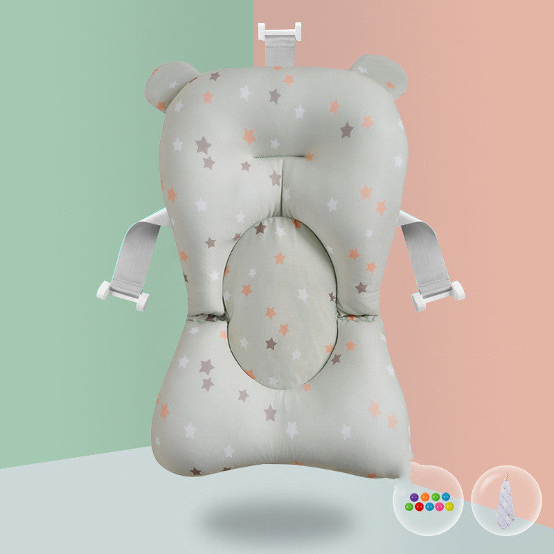 Infant bath pillow with star pattern, ear-shaped headrest, and safety straps against a split peach and mint background. Includes colorful water balls and a bathing cap.