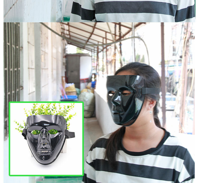 Person wearing a shiny black mask in an outdoor setting. Inset shows close-up of the mask with green foliage visible through its eye holes. Person wears a black-and-white striped shirt.