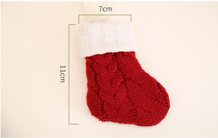 A small knitted red stocking with a white cuff, measuring 11cm in height and 7cm in width, lies flat on a light background.