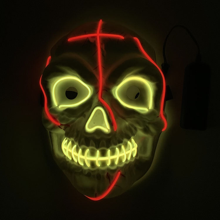 A glowing skull mask with neon yellow eyes, nose, and mouth lines, accented by red neon lines on the forehead, cheeks, and chin. The mask is set against a dark background.