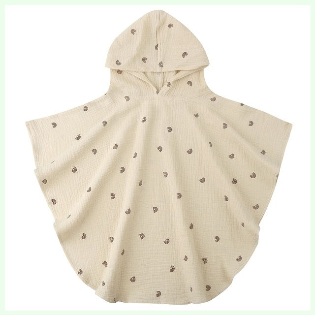 Cream-colored hooded poncho with a simple pattern of small brown rainbows. The material appears soft and lightweight, designed for casual or cozy wear.