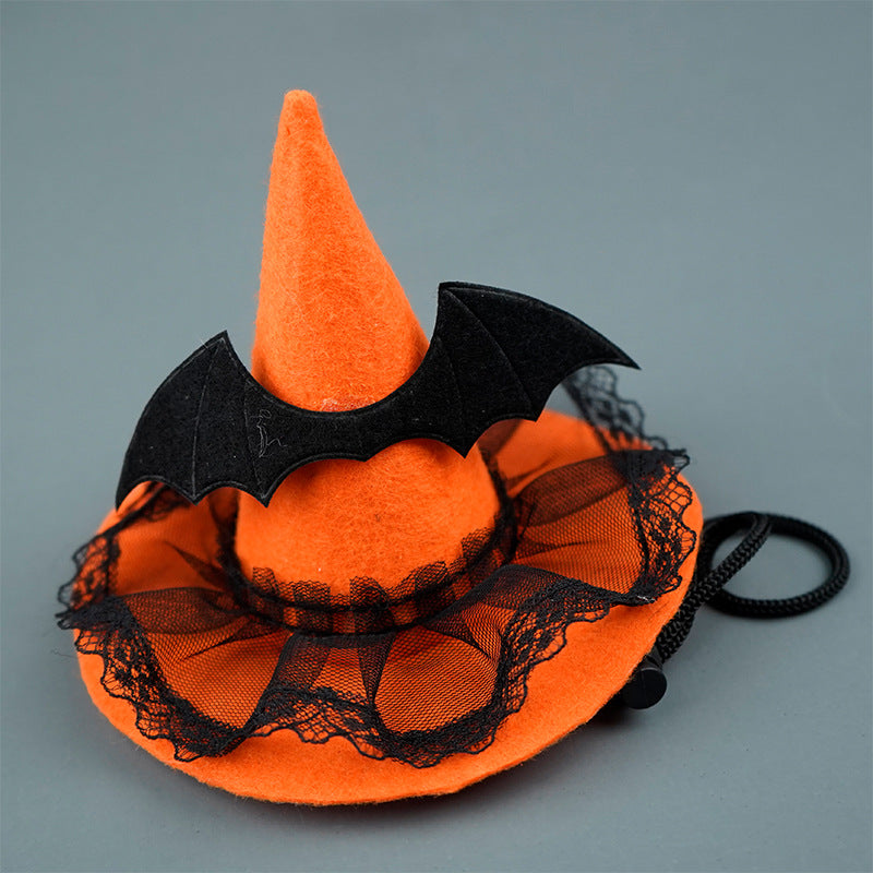An orange felt witch hat with black lace trim, adorned with a black bat decoration. It has an adjustable strap attached, set against a plain gray background.