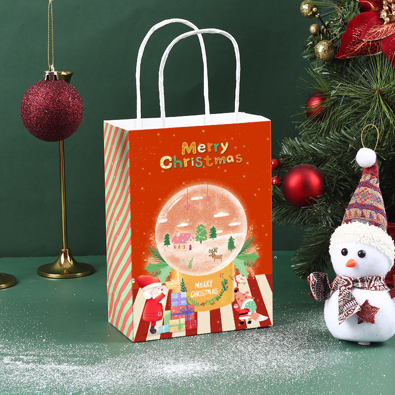 Christmas-themed scene with a festive gift bag featuring a snow globe design, surrounded by ornaments, a tree, and a snowman wearing a scarf and hat on a green background.
