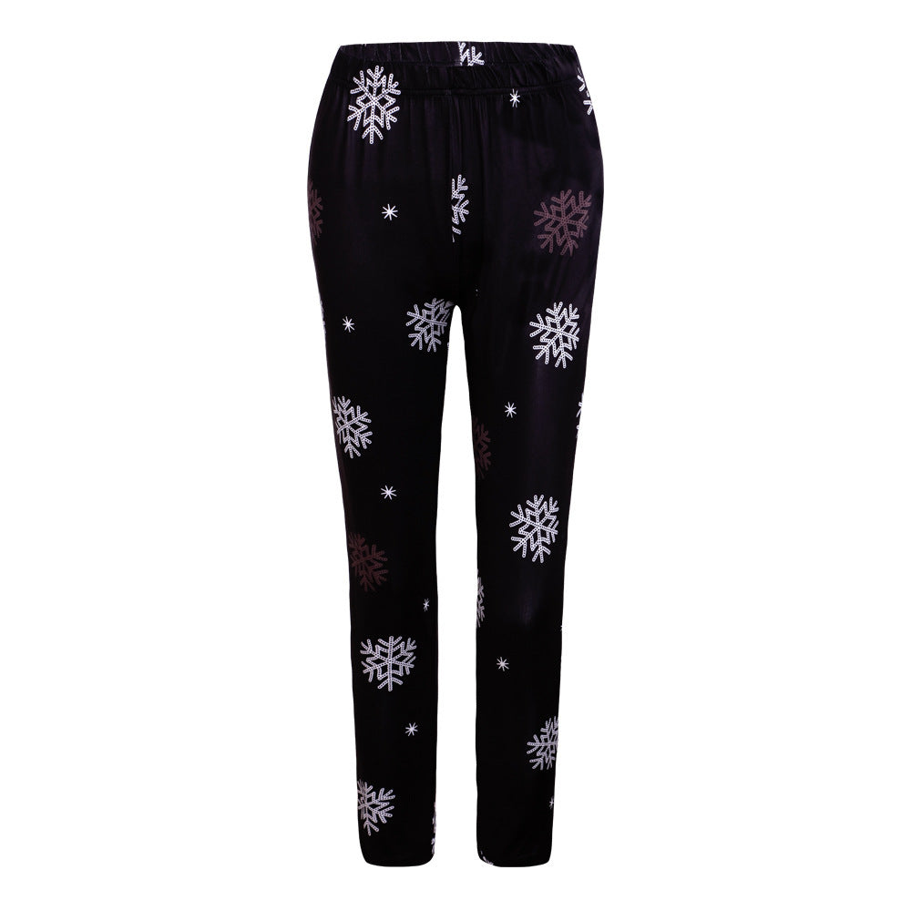 Black pajama pants with an elastic waistband, printed with large white and brown snowflake patterns.