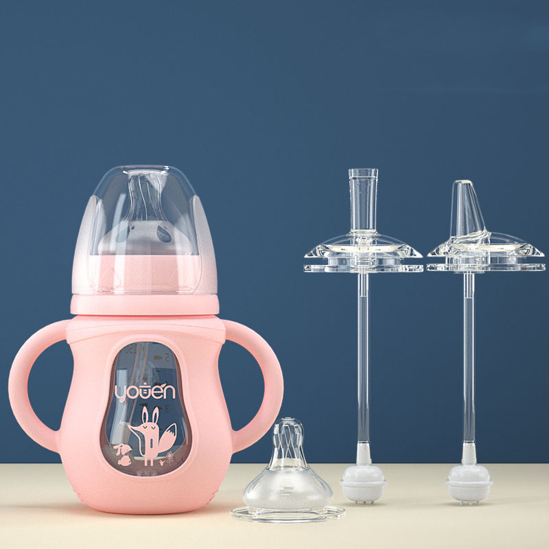 Pink sippy cup with dual handles and a fox design, featuring a nipple and two additional clear straw components, placed against a blue background on a cream-colored surface.