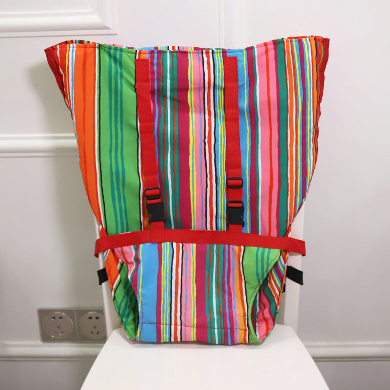 A colorful striped fabric bag with vertical lines in green, red, pink, blue, and orange. It has red straps and is placed on a white chair against a white wall.