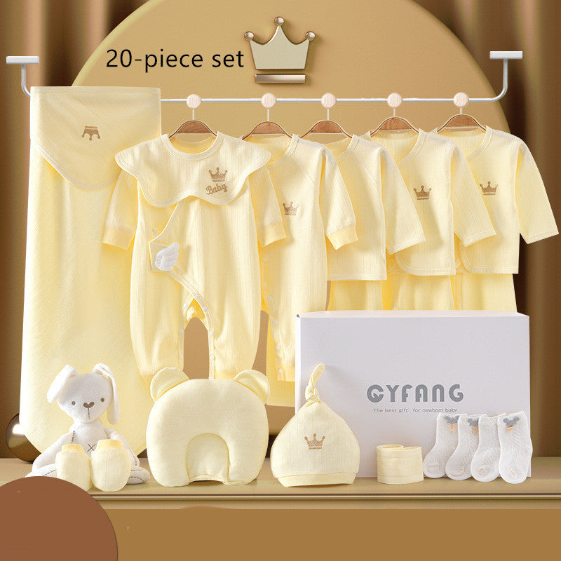 A 20-piece baby clothing set in soft yellow includes onesies, tops, pants, a plush toy, socks, a pillow, and a hat, all adorned with crown motifs, displayed on a rack and table.