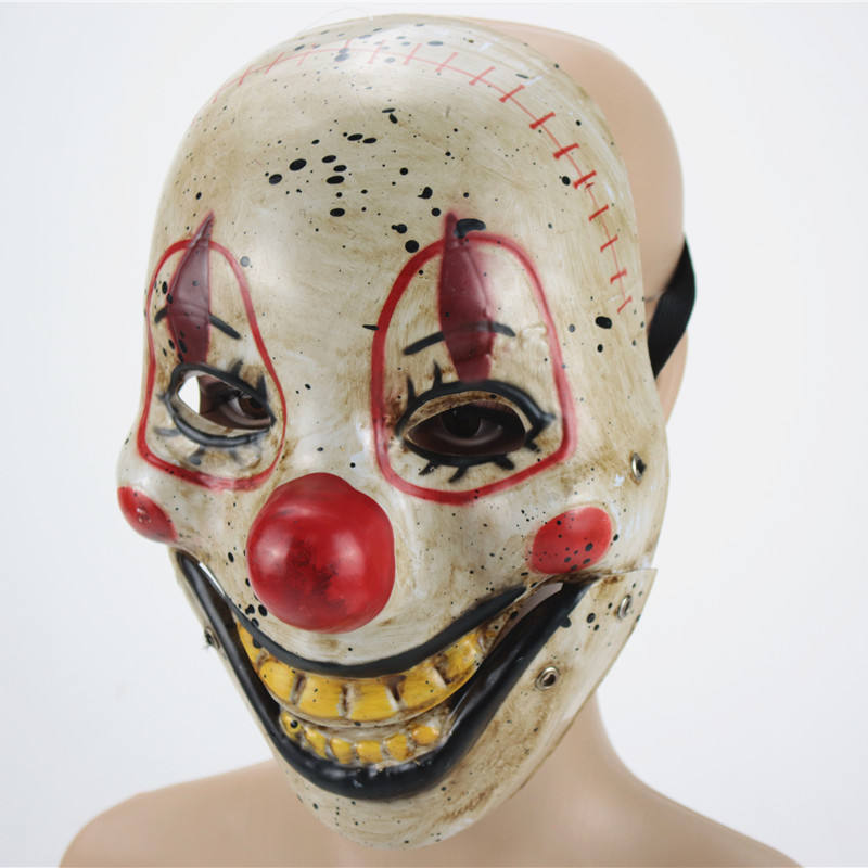 Creepy clown mask with red nose, exaggerated smile, and distressed look. Features include yellow teeth, painted red cheeks, and black speckled details on a beige background.