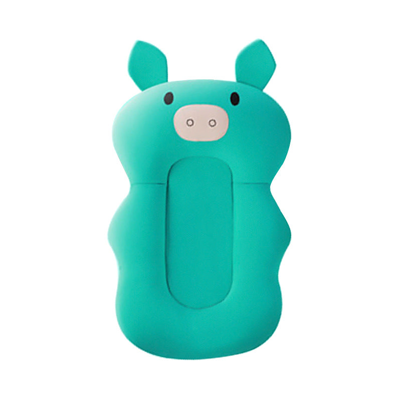 Aqua green sponge-like baby bath cushion in the shape of a playful pig with ears, eyes, and a nostril pattern on its face. The cushion is contoured for comfort.