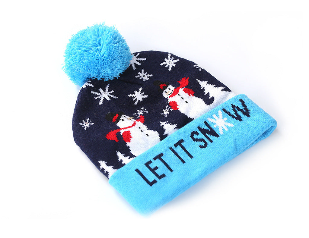Blue and navy knit hat with a snowman and snowflakes design. Features a fluffy blue pom-pom and "LET IT SNOW" text on the brim.