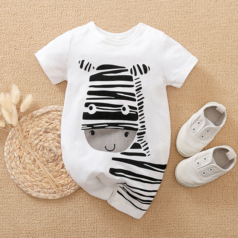 Baby outfit with a white onesie featuring a smiling zebra design, paired with matching white shoes. A woven mat and decorative dried flowers are placed beside the ensemble.