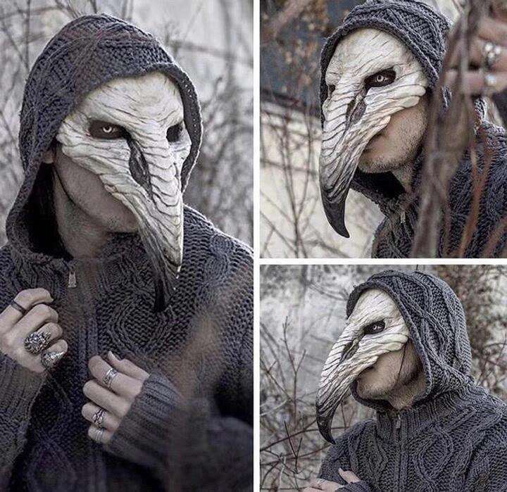 Person wearing a detailed bird-like mask with a long beak, in a gray knitted hoodie. Set outdoors among barren branches, shown from three different angles.