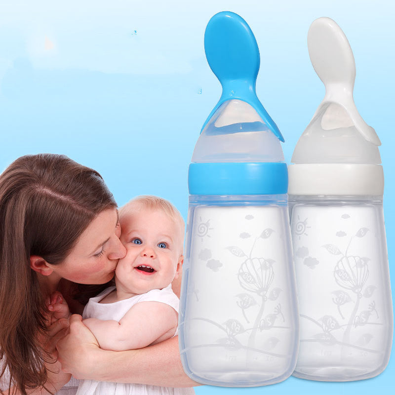 A mother lovingly kisses her smiling baby, beside two baby bottles with spoon-shaped tops, one blue and one white, against a light blue background with floral designs.