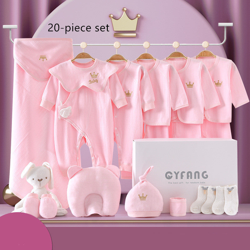 Pink baby clothing set including onesies, hats, a pillow, socks, stuffed toy, and a blanket, all with crown detail, displayed with a gift box on a purple background.